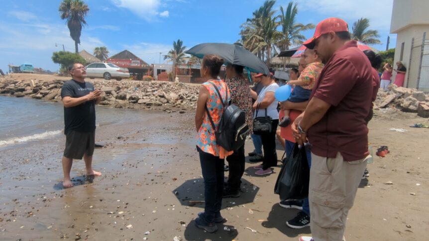 Pastor Licho praying in front of the brothers and sisters at the beach